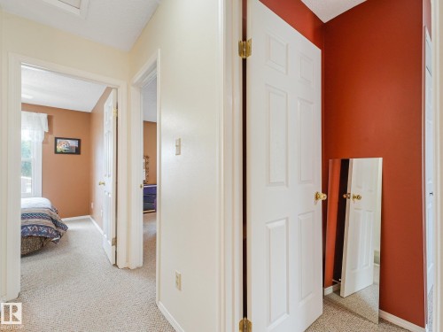 Neutral-toned carpet flooring throughout, with white six-panel doors and brass hardware - 18417 66 Avenue Nw, Edmonton, AB - Indoor Photo Showing Other Room