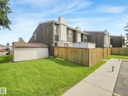 Exterior featuring vertical wood siding, stucco accents, and a fenced yard with a storage shed - 18417 66 Avenue Nw, Edmonton, AB - Outdoor