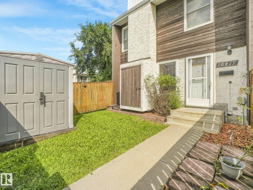 Exterior featuring mixed material siding, concrete walkway, a gray storage shed, and a wooden fence - 18417 66 Avenue Nw, Edmonton, AB - Outdoor