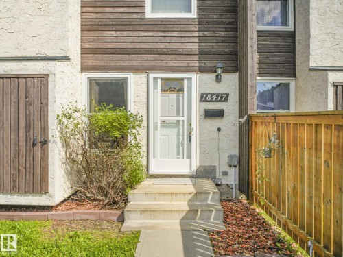 Stucco and wood-finish exterior with a white entry door - 18417 66 Avenue Nw, Edmonton, AB - Outdoor