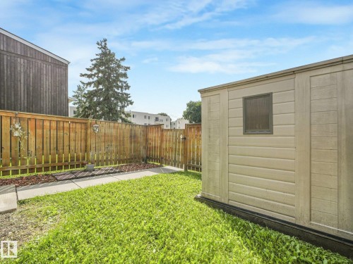 Fenced backyard featuring a storage shed with a window, a wooden fence, a grass lawn, and concrete paver pathway - 18417 66 Avenue Nw, Edmonton, AB - Outdoor
