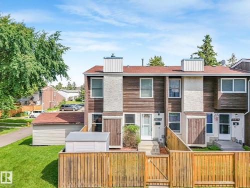 Townhouse exterior with wood siding and stucco accents, a gabled roof, and individual fenced front yards - 18417 66 Avenue Nw, Edmonton, AB - Outdoor