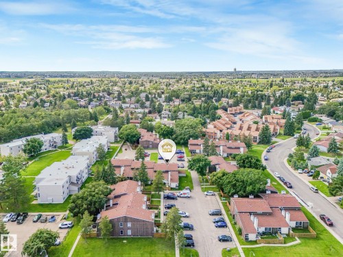 Expansive residential development featuring multiple multi-unit buildings, mature trees, and paved parking areas - 18417 66 Avenue Nw, Edmonton, AB - Outdoor With View