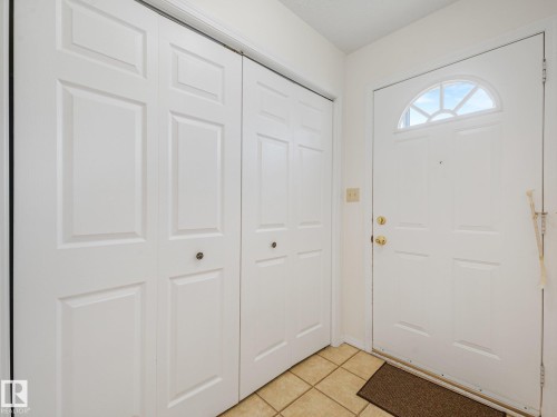 Tile flooring, raised panel doors, and a front entry door with an arched transom - 18417 66 Avenue Nw, Edmonton, AB - Indoor Photo Showing Other Room