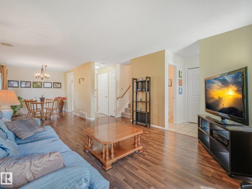 Wood-finish flooring throughout, with a dedicated dining area featuring an overhead chandelier - 18417 66 Avenue Nw, Edmonton, AB - Indoor Photo Showing Living Room