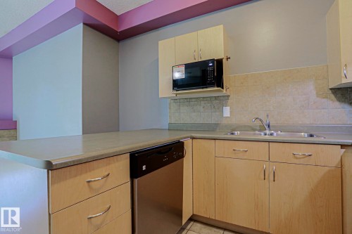 Kitchen featuring light wood-finish cabinetry, stainless steel dishwasher, and built-in microwave - #101 10118 95 St Nw Nw, Edmonton, AB - Indoor Photo Showing Kitchen With Double Sink