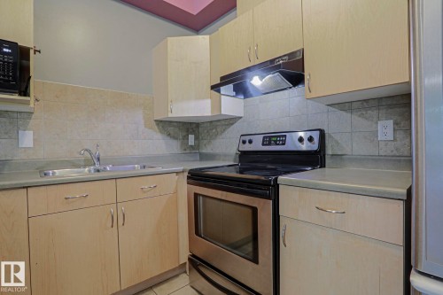 Light wood-finish cabinetry, stainless steel oven, stainless steel sink, and tiled backsplash - #101 10118 95 St Nw Nw, Edmonton, AB - Indoor Photo Showing Kitchen With Double Sink