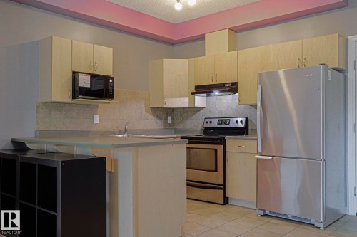 Kitchen with light wood-finish cabinetry, stainless steel appliances, and a tiled backsplash - #101 10118 95 St Nw Nw, Edmonton, AB - Indoor Photo Showing Kitchen