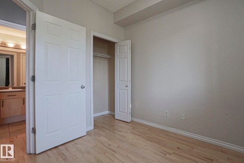 Light wood-finish flooring, neutral wall paint, and a built-in closet with shelving - #101 10118 95 St Nw Nw, Edmonton, AB - Indoor Photo Showing Other Room