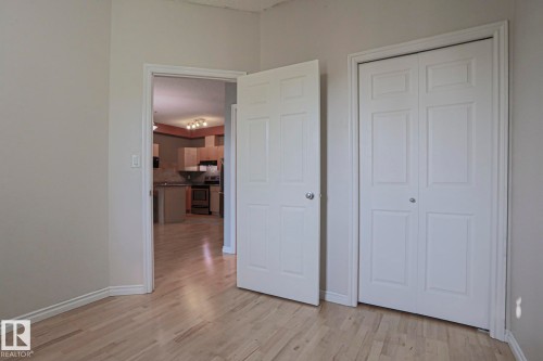 Wood-finish flooring throughout, white panel doors, and a double bi-fold closet - #101 10118 95 St Nw Nw, Edmonton, AB - Indoor Photo Showing Other Room