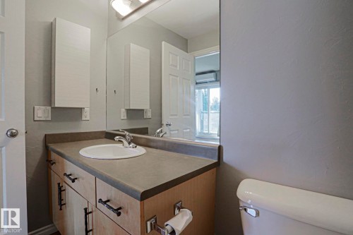Neutral wall paint with a built-in vanity, integrated sink, and an expansive wall mirror - #101 10118 95 St Nw Nw, Edmonton, AB - Indoor Photo Showing Bathroom