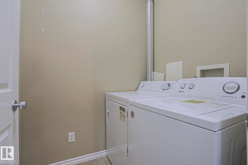 Laundry area with wall-mounted dryer vent, white door, and neutral wall paint - #101 10118 95 St Nw Nw, Edmonton, AB - Indoor Photo Showing Laundry Room