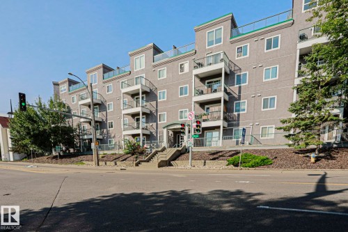 Multi-story building featuring balconies with glass railings, an arched entry, and a flat roofline - #101 10118 95 St Nw Nw, Edmonton, AB - Outdoor With Balcony