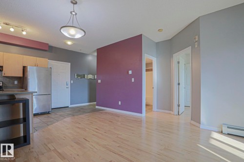 Hardwood-finish flooring, stainless steel refrigerator, contemporary pendant lighting, recessed ceiling lights, and light wood-finish cabinetry - #101 10118 95 St Nw Nw, Edmonton, AB - Indoor Photo Showing Kitchen