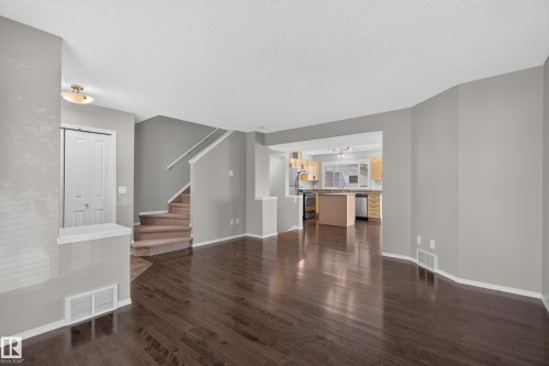 Dark wood-finish flooring throughout, light gray wall paint, and a staircase with carpeted treads - 6008 South Terwillegar Boulevard Nw, Edmonton, AB - Indoor Photo Showing Other Room