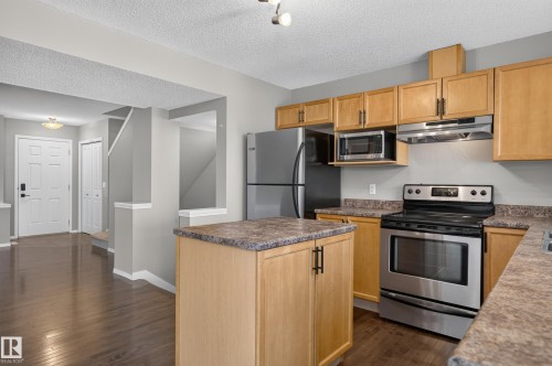 Kitchen featuring wood-finish cabinetry, stainless steel appliances, a center island with storage, and wood-finish flooring - 6008 South Terwillegar Boulevard Nw, Edmonton, AB - Indoor Photo Showing Kitchen
