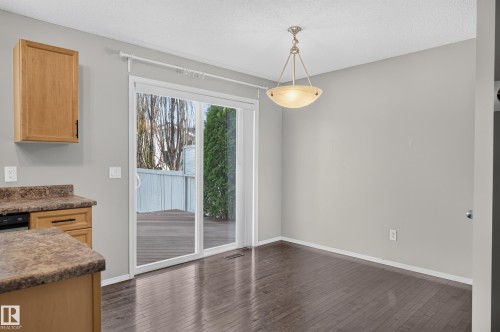 Sliding glass door to an outdoor deck, wood-finish flooring, and a semi-flush mount ceiling fixture - 6008 South Terwillegar Boulevard Nw, Edmonton, AB - Indoor