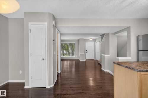 Hardwood-finish flooring, light gray wall paint, white trim, recessed lighting, and a partial kitchen counter with a stone-finish surface - 6008 South Terwillegar Boulevard Nw, Edmonton, AB - Indoor Photo Showing Other Room
