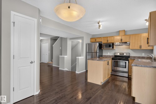 Kitchen featuring wood-finish cabinetry, stainless steel appliances, and a central island with a countertop - 6008 South Terwillegar Boulevard Nw, Edmonton, AB - Indoor Photo Showing Kitchen With Double Sink