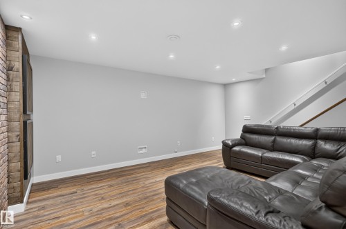 Reclaimed wood-finish accent wall with integrated fireplace, wood-finish flooring, recessed lighting, and a staircase with a wood handrail - 6008 South Terwillegar Boulevard Nw, Edmonton, AB - Indoor