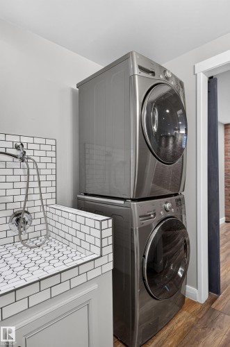 Stacked laundry appliances, white subway tile surround, patterned tile basin, chrome fixtures, wood-finish flooring - 6008 South Terwillegar Boulevard Nw, Edmonton, AB - Indoor Photo Showing Laundry Room