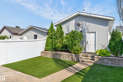 Light gray siding exterior with a white entry door, surrounded by mature landscaping - 6008 South Terwillegar Boulevard Nw, Edmonton, AB - Outdoor