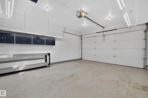 Attached overhead cabinetry, workbench, garage door opener, and epoxy flooring - 6008 South Terwillegar Boulevard Nw, Edmonton, AB - Indoor Photo Showing Garage