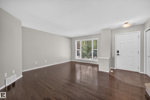 Hardwood flooring throughout the main area, large window with horizontal blinds, and a paneled entry door - 6008 South Terwillegar Boulevard Nw, Edmonton, AB - Indoor Photo Showing Other Room