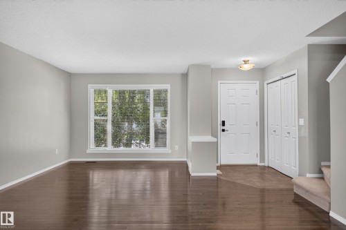 Hardwood-finish flooring, large window with blinds, front entry door with smart lock, built-in storage closet, and staircase with carpeted treads - 6008 South Terwillegar Boulevard Nw, Edmonton, AB - Indoor Photo Showing Other Room