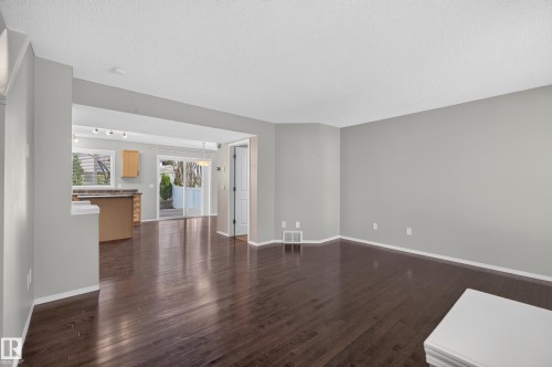 Spacious living area featuring dark wood-finish flooring, light grey painted walls, and an open concept layout - 6008 South Terwillegar Boulevard Nw, Edmonton, AB - Indoor Photo Showing Other Room