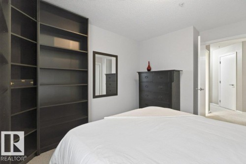 Built-in shelving unit, neutral wall color, and light-toned carpet - #201 10528 77 Av Nw, Edmonton, AB - Indoor Photo Showing Bedroom