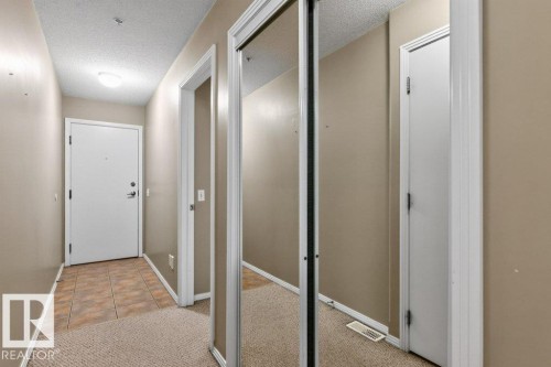 Entryway featuring durable tile flooring, plush carpeting, a flush-mount ceiling light, and mirrored closet doors - #201 10528 77 Av Nw, Edmonton, AB - Indoor Photo Showing Other Room