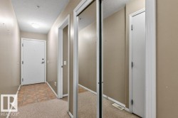 Entryway featuring durable tile flooring, plush carpeting, a flush-mount ceiling light, and mirrored closet doors - 