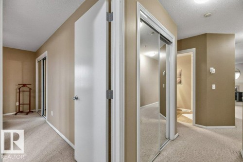 Hallway featuring light neutral wall paint, light-toned carpet flooring, recessed lighting, and mirrored closet doors - #201 10528 77 Av Nw, Edmonton, AB - Indoor Photo Showing Other Room