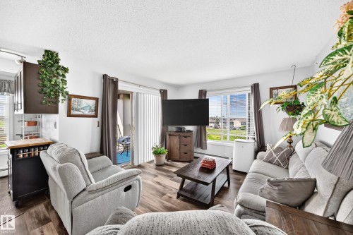 Wood-finish flooring throughout, bright white walls, and a sliding glass door providing outdoor access - #401 5390 Chappelle Rd Sw, Edmonton, AB 