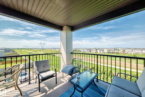 Covered outdoor balcony with a black metal railing and concrete flooring - #401 5390 Chappelle Rd Sw, Edmonton, AB 