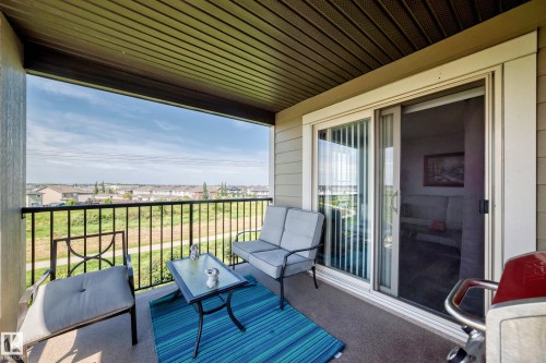 Covered balcony with a slatted ceiling, durable flooring, and a sliding glass door - #401 5390 Chappelle Rd Sw, Edmonton, AB 