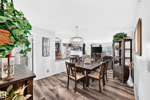 Wood-finish flooring throughout, with a crystal chandelier, and a black countertop bar - #401 5390 Chappelle Rd Sw, Edmonton, AB 