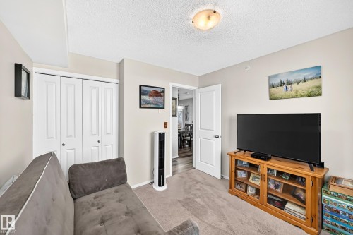 Neutral wall color, carpeted flooring, white bi-fold closet doors, white interior door, and flush mount ceiling light fixture - #401 5390 Chappelle Rd Sw, Edmonton, AB 