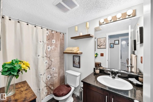 Vanity with dark wood cabinetry and a dark stone-finish countertop - #401 5390 Chappelle Rd Sw, Edmonton, AB 