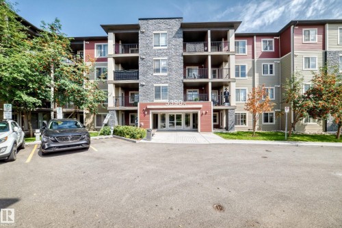 Multi-story building featuring stone and siding exterior, multiple balconies with metal railings, and a prominent main entrance with glass doors - #401 5390 Chappelle Rd Sw, Edmonton, AB 