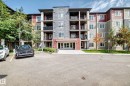Multi-story building featuring stone and siding exterior, multiple balconies with metal railings, and a prominent main entrance with glass doors - #401 5390 Chappelle Rd Sw, Edmonton, AB  - Outdoor With Balcony With Facade 