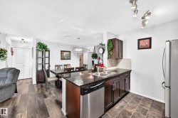 Kitchen island with dark countertops, stainless steel sink, and built-in dishwasher - 