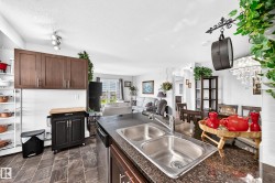 Open-concept kitchen with dark cabinetry, granite-style countertops, and a double stainless steel sink - 