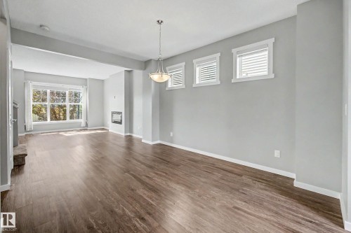 Wood-finish flooring throughout, recessed fireplace, and a contemporary pendant light fixture - 118 Southfork Road, Leduc, AB - Indoor