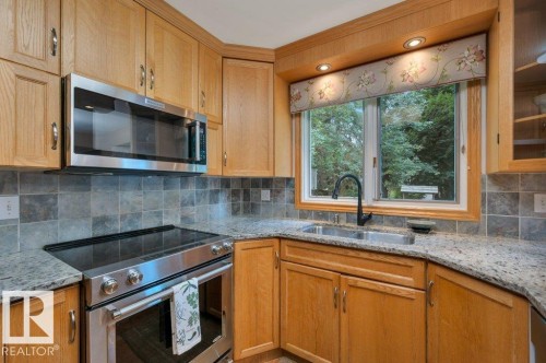 Oak cabinetry with stainless steel appliances & granite counter tops - 5620 151 Street Nw, Edmonton, AB - Indoor Photo Showing Kitchen With Double Sink