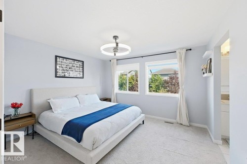 White ceiling fan with integrated lighting, dual windows with black curtain rods, light-colored carpeting, and a visible doorway to an adjacent space - 4242 Chichak Close Sw, Edmonton, AB - Indoor Photo Showing Bedroom