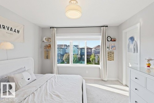 Plush carpeted flooring, a large window with white trim, and a flush mount ceiling light fixture - 4242 Chichak Close Sw, Edmonton, AB - Indoor Photo Showing Bedroom