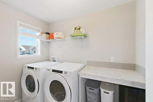 Dedicated laundry area featuring a window, built-in wire shelving, and a countertop with a subway tile backsplash - 4242 Chichak Close Sw, Edmonton, AB - Indoor Photo Showing Laundry Room