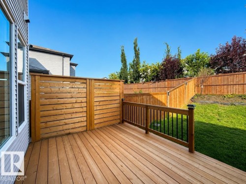 Expansive wood-finish deck with a privacy screen and black metal balusters - 4242 Chichak Close Sw, Edmonton, AB - Outdoor With Deck Patio Veranda